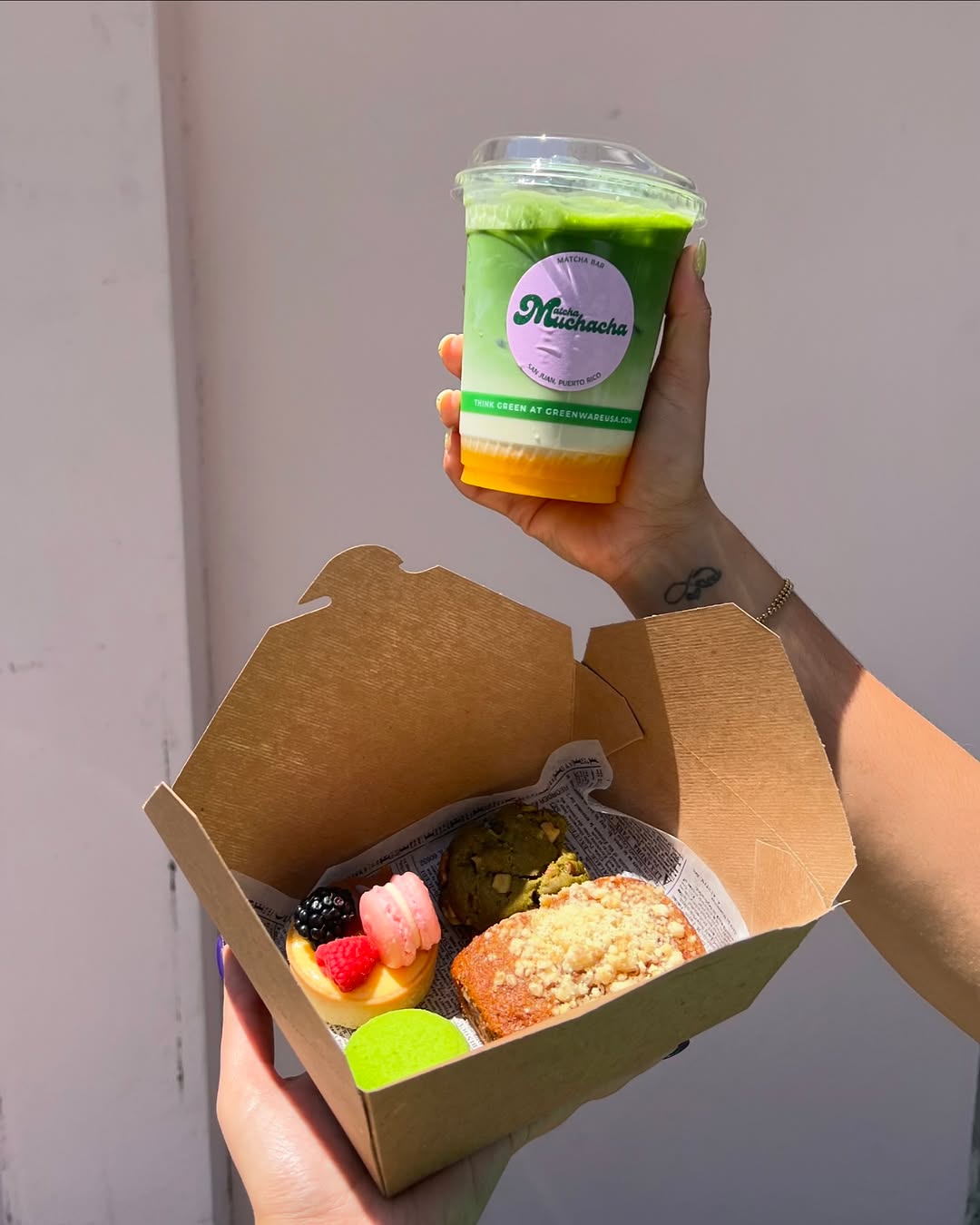 Matcha frío de Matcha Muchacha junto a una caja de repostería
